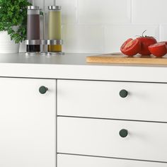 two tomatoes on a cutting board next to some condiments