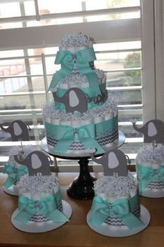 a baby shower cake with elephant decorations on the top and diaper cakes in the bottom