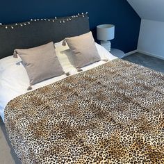 a leopard print comforter on a bed in a room with blue walls and carpet