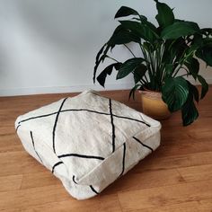 a potted plant sitting on top of a wooden floor next to a white pillow