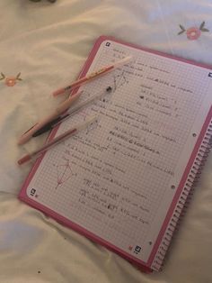 two pencils are laying on top of a notebook