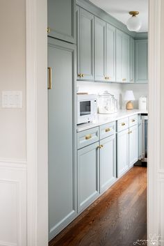 a kitchen with light blue cabinets and wood floors