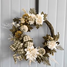 a wreath hanging on the front door with flowers and leaves attached to it's sides