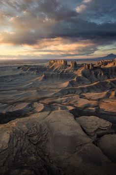 the sun is setting in the distance over some desert land with rocks and sand on it