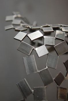 an abstract piece of metal is shown in this close up photo, with many smaller pieces scattered around it