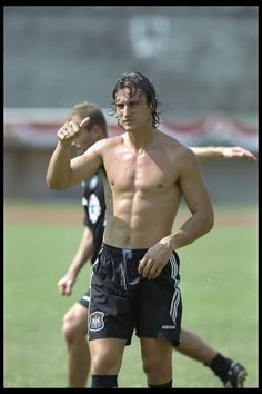 a shirtless man standing on top of a soccer field