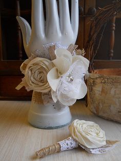 a white vase with flowers on it next to a decorative object in the shape of a hand