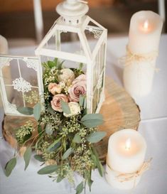 an arrangement of flowers and candles on a wooden slice at a wedding reception in white