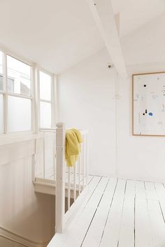 an empty room with white walls and wood flooring on the bottom level has a yellow blanket draped over the railing