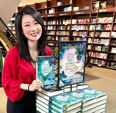 a woman standing in front of a stack of books