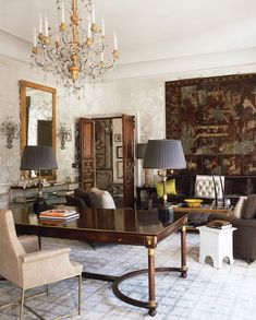 a living room filled with lots of furniture and a chandelier hanging from the ceiling