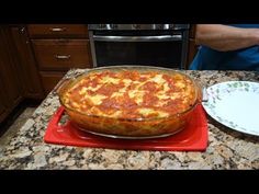 a large pizza sitting on top of a red platter next to a white plate