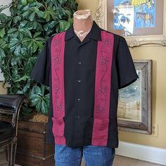 This is a handsome, vintage Cubavera casual shirt in black and burgundy with black and gray embroidered details. The easy care shirt is made of a soft but substantial rayon/polyester blend, so it drapes nicely. It has a spread collar and two front pockets at the hip. The short sleeves have button detail and the left sleeve bears the embroidered pineapple logo.  This shirt is in excellent vintage condition with no stains or flaws.  It's marked size L, measuring 47"" at the chest and hip, and is 2 Vintage Short Sleeve Shirt With Tropical Print, Vintage Short Sleeve Shirt With Hibiscus Print, Black Embroidered Button-up Shirt, Vintage Button-up Hawaiian Shirt For Summer, Embroidered Pineapple, Vintage Black Shirt With Button Closure, Tropical Shirt, Vintage Tropical, 1960s Style