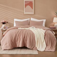 a bed with pink sheets and pillows in a bedroom