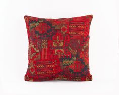 a red and black pillow sitting on top of a white wall