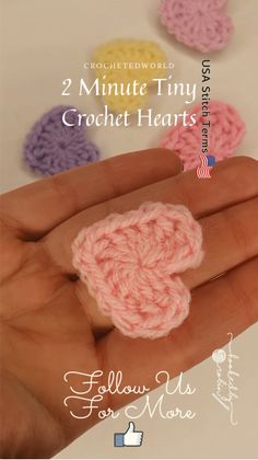 someone is holding their hand with some crochet hearts on it