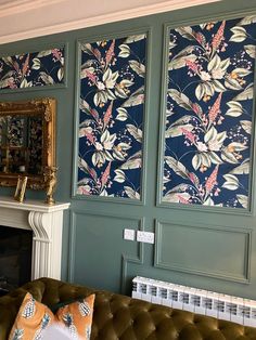 a living room with green walls and floral wallpaper on the fireplace mantels