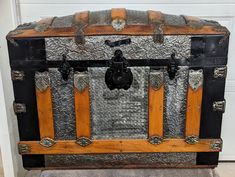 an old trunk is sitting in front of a white door and has metal accents on it