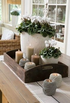 a tray with candles and flowers on top of a table in front of a window