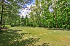 a tennis court surrounded by trees and benches