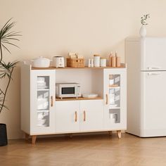 a white refrigerator freezer sitting next to a microwave oven on top of a wooden table