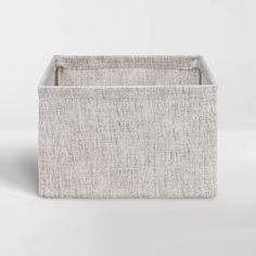 a white fabric storage bin with handles on the top and bottom, in front of a plain background