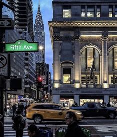 people are crossing the street in front of an old building with a sign that says fifth ave