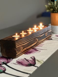 candles are lit on a wooden piece of wood that is sitting on top of a table