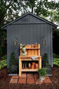 an outdoor potting shed with pots and plants on the outside, along with wooden shelves