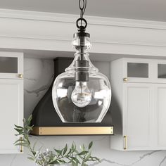 a light fixture hanging from the ceiling in a kitchen with marble counter tops and white cabinets