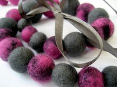 several balls of felt are tied together on a white surface with a gray and pink ribbon