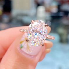 a close up of a person's hand holding a ring with a diamond on it