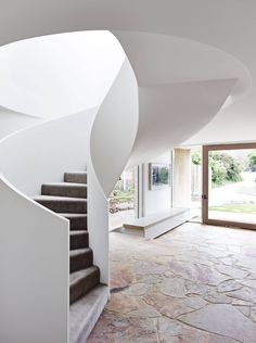 a spiral staircase in a house with stone flooring and white walls, leading up to the second floor