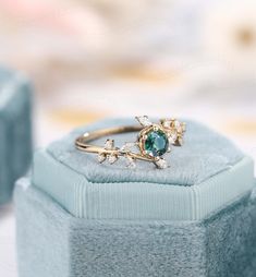 an opal and diamond ring sitting on top of a blue velvet box