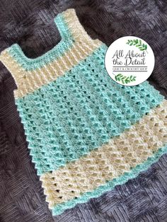 a crocheted baby dress sitting on top of a gray blanket with the words all about