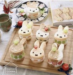 several sandwiches are arranged in the shape of buns with bunny faces on them, along with strawberries and grapes