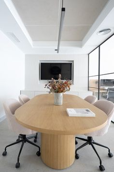 a large wooden table with chairs around it in front of a flat screen tv mounted on the wall