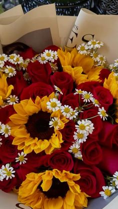 a bouquet of sunflowers and red roses in a paper bag