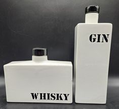 two white flasks with the words gin and whiskey written on them are shown