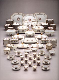 a table topped with lots of white and brown dishes covered in saucers, cups and saucers