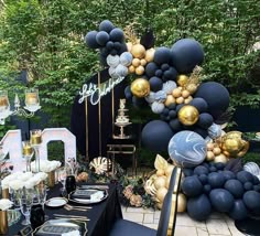 a table set up with black and gold balloons