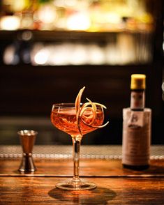 two glasses filled with drinks sitting on top of a wooden table