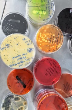 six different colored cups with writing on them sitting next to each other in front of a metal tray