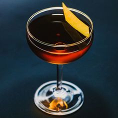 a close up of a drink in a glass with a lemon wedge on the rim