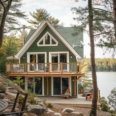 there is a green house with white trim on the front and second story that has a deck