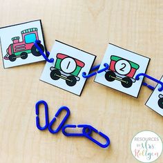 some blue paper clips sitting on top of a wooden table next to pictures and scissors