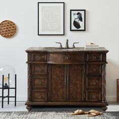 a bathroom vanity with two pictures on the wall and a rug in front of it