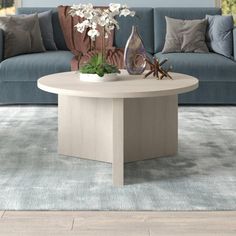 a living room with blue couches and white flowers in vases on the coffee table