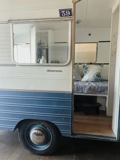 a blue and white trailer with a bed in it's side door open to the other side