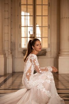 a woman sitting on the floor in a white dress